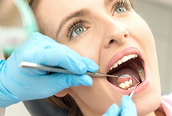 Patientin bei der Kontrolle mit offenem Mund und Mundspiegel