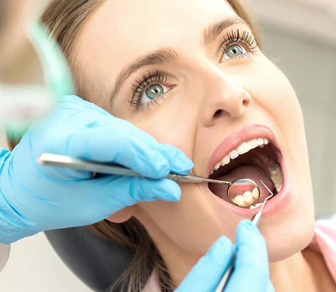 Patientin bei der Kontrolle mit offenem Mund und Mundspiegel